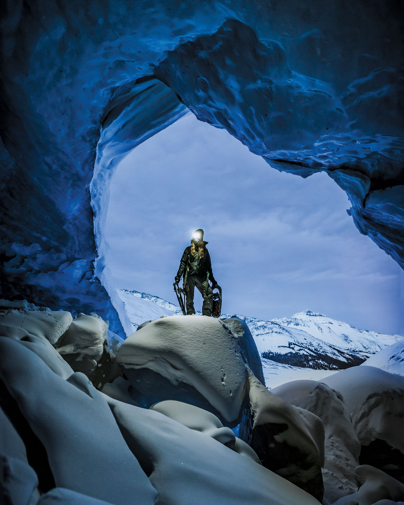 A person with snowshoes stands in an ice cave in the magical world of snow and ice