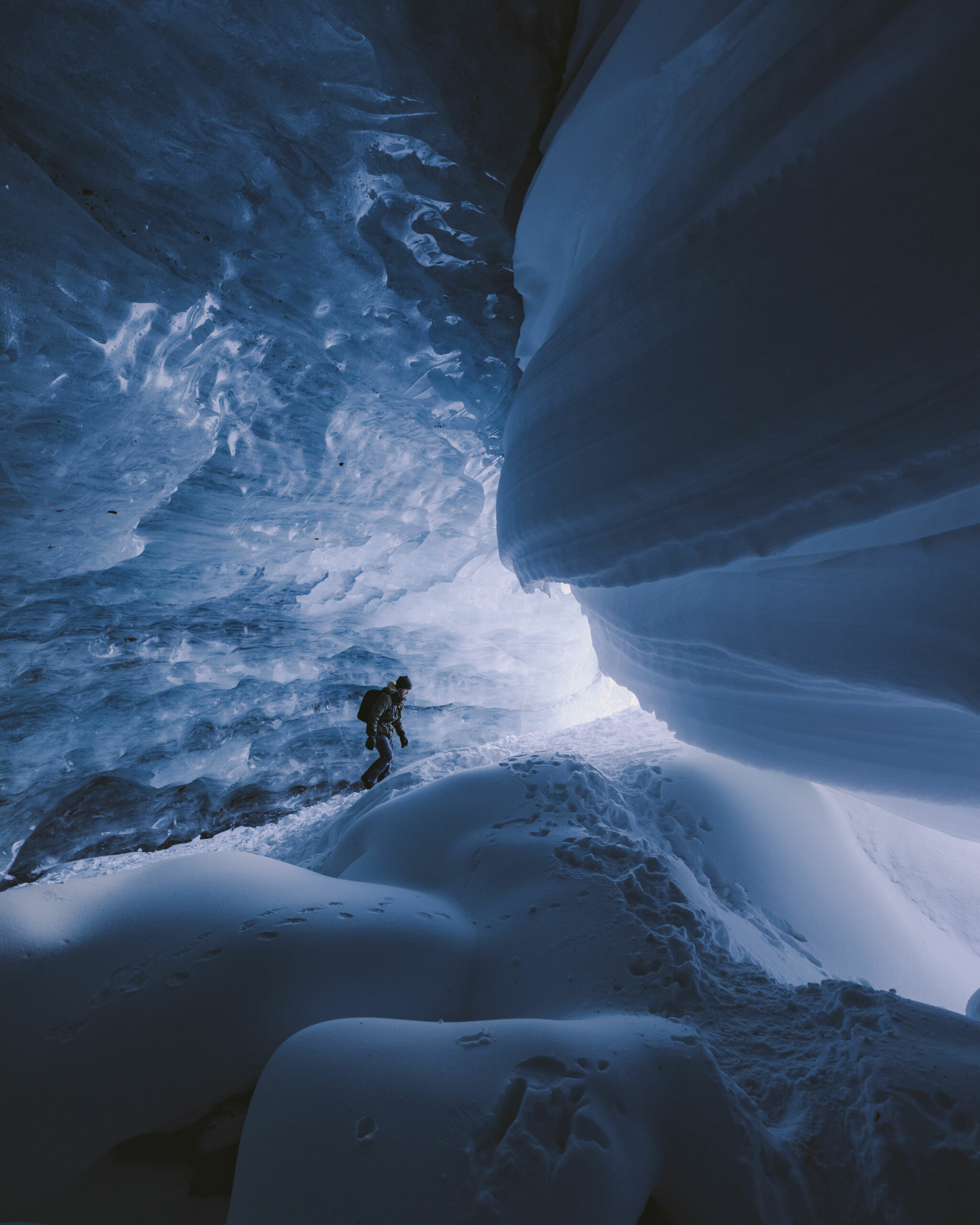 A person in an otherworldly looking ice cave in the magical world of snow and ice