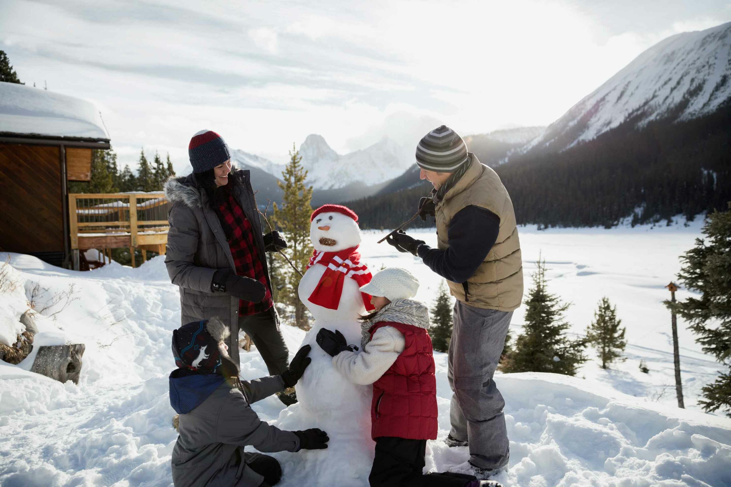 A family builds a snowman by Mount Engadine Lodge