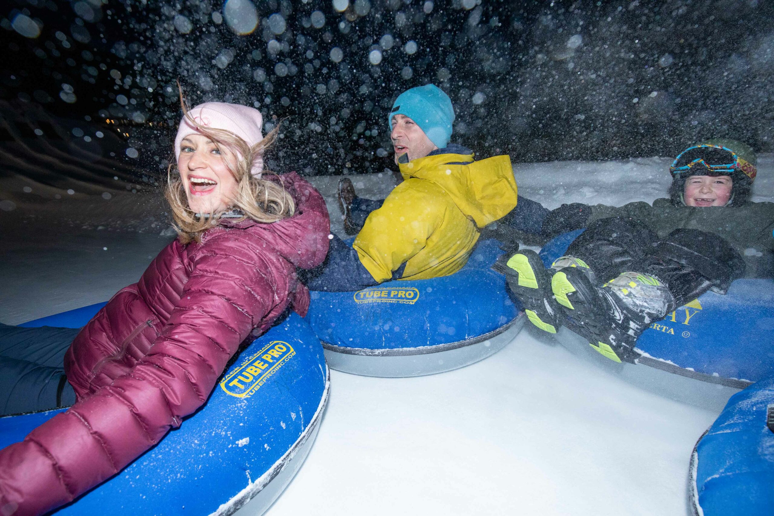 A family spins in the tube lane at Mount Norquay after dark.