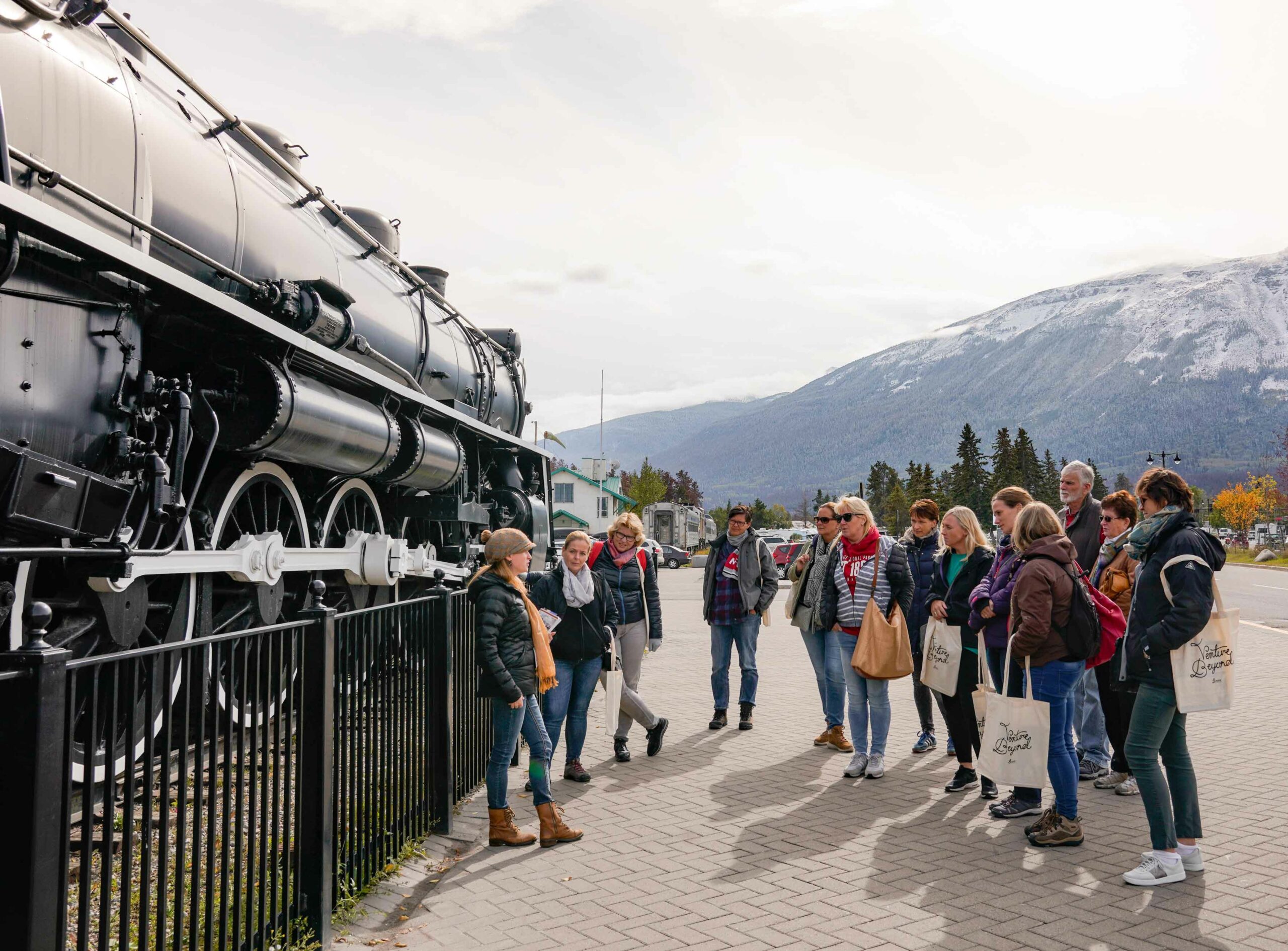 A group of people gather around the old steam engine at the Jasper train station as part of the Downtown Foodie Tour with Jasper Food Tours