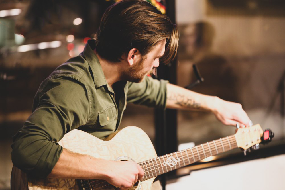 A person tunes a guitar at an Open Mic Night at The Old Grind