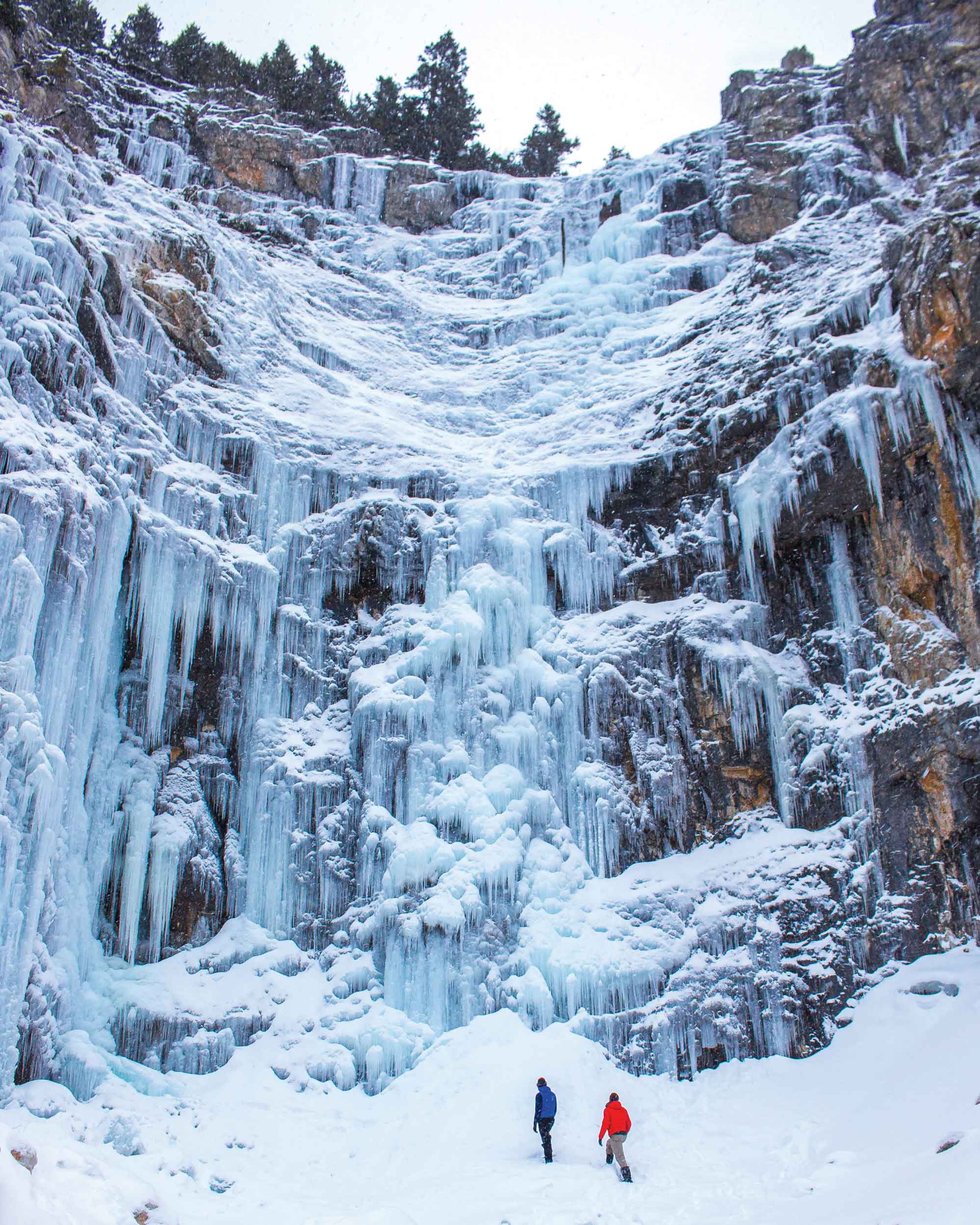 Two people admire ice falls in Waterton in winter.
