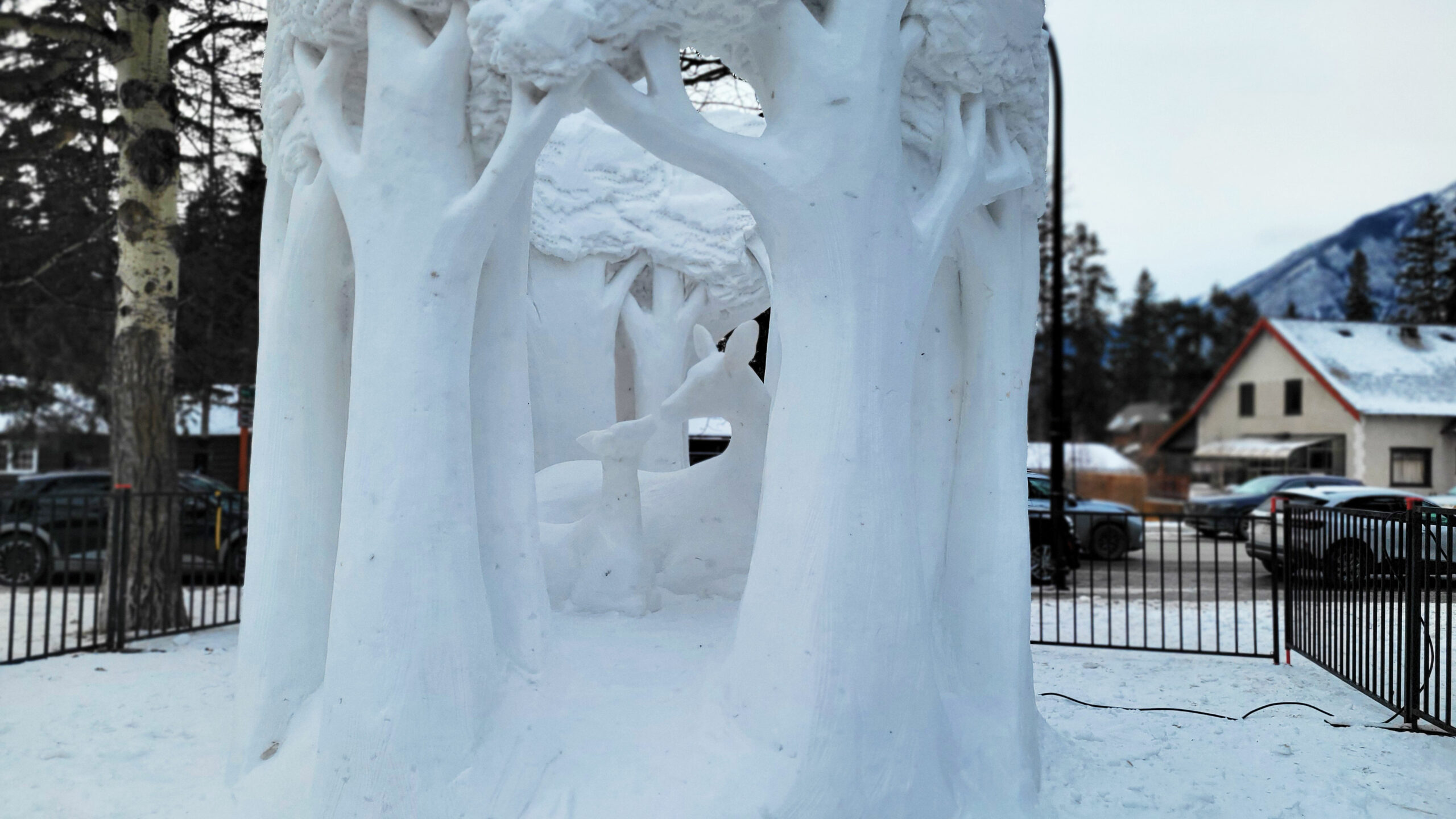A beautiful snow sculpture featuring a doe and a fawn in a circle of trees in Banff as part of the SnowDays festival