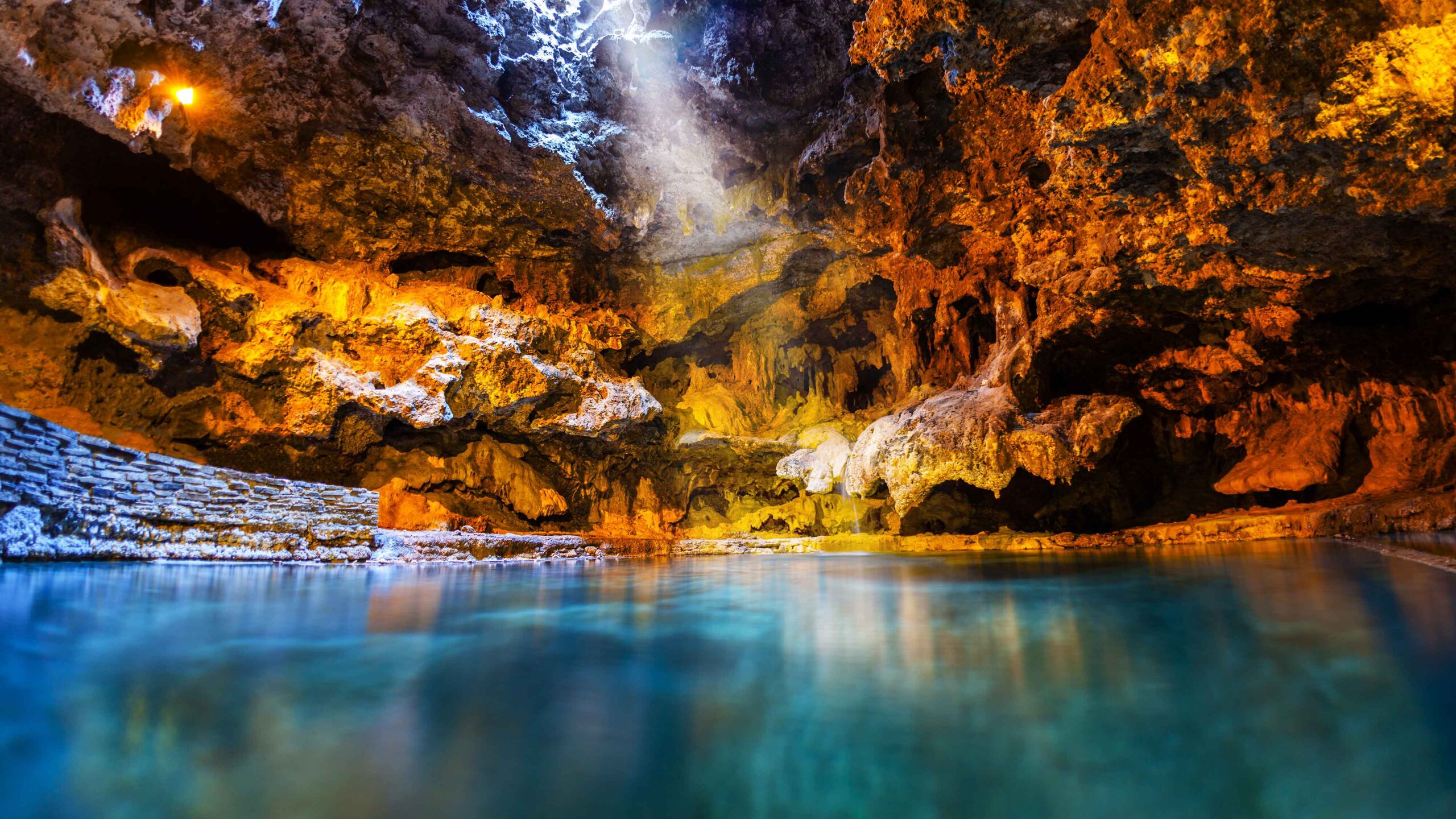 The turquoise waters of the Cave and Basin with light shining through the cave. This National Historic Site is free for the summer.
