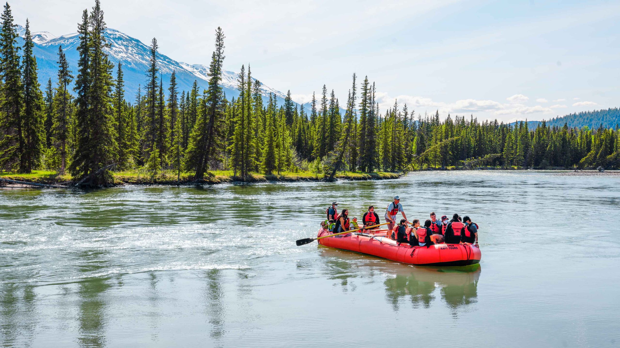 People enjoy a gentle float down the Athabasca River with Jasper Raft Tours.