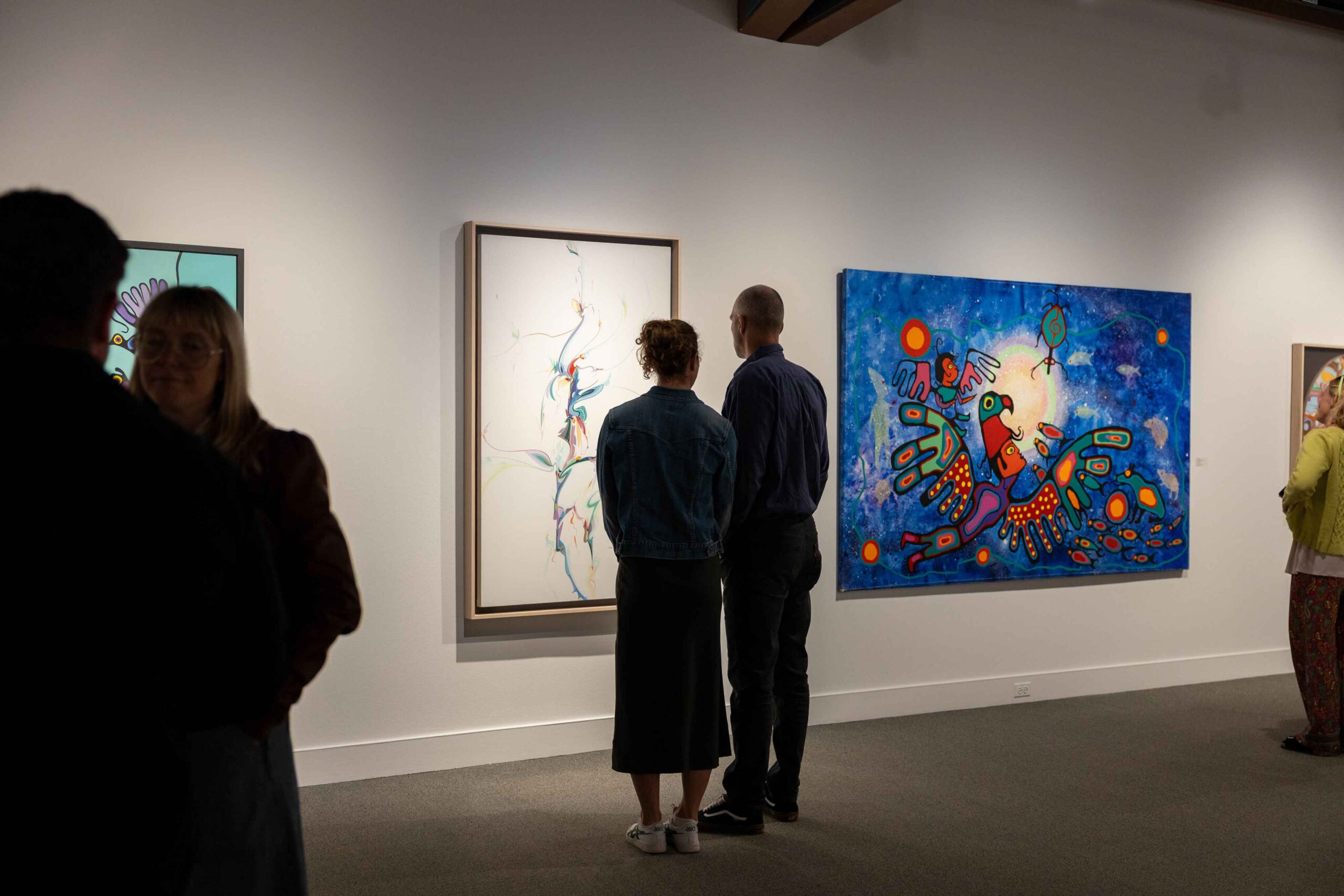 Two people look at a colourful painting during the opening night of The Ancestors Are Talking, an exhibit at The Whyte Museum