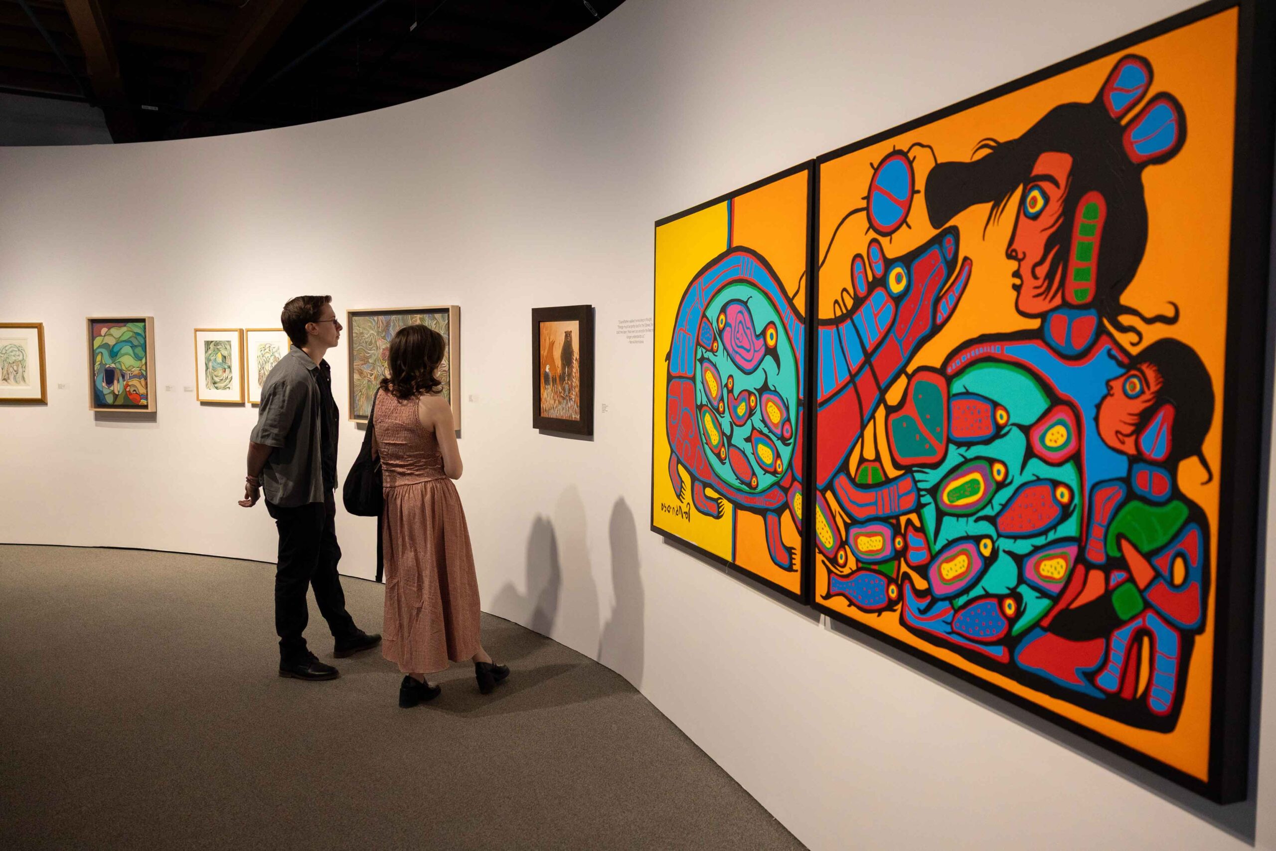 Two people look at a colourful painting during the opening night of The Ancestors Are Talking, an exhibit at The Whyte Museum