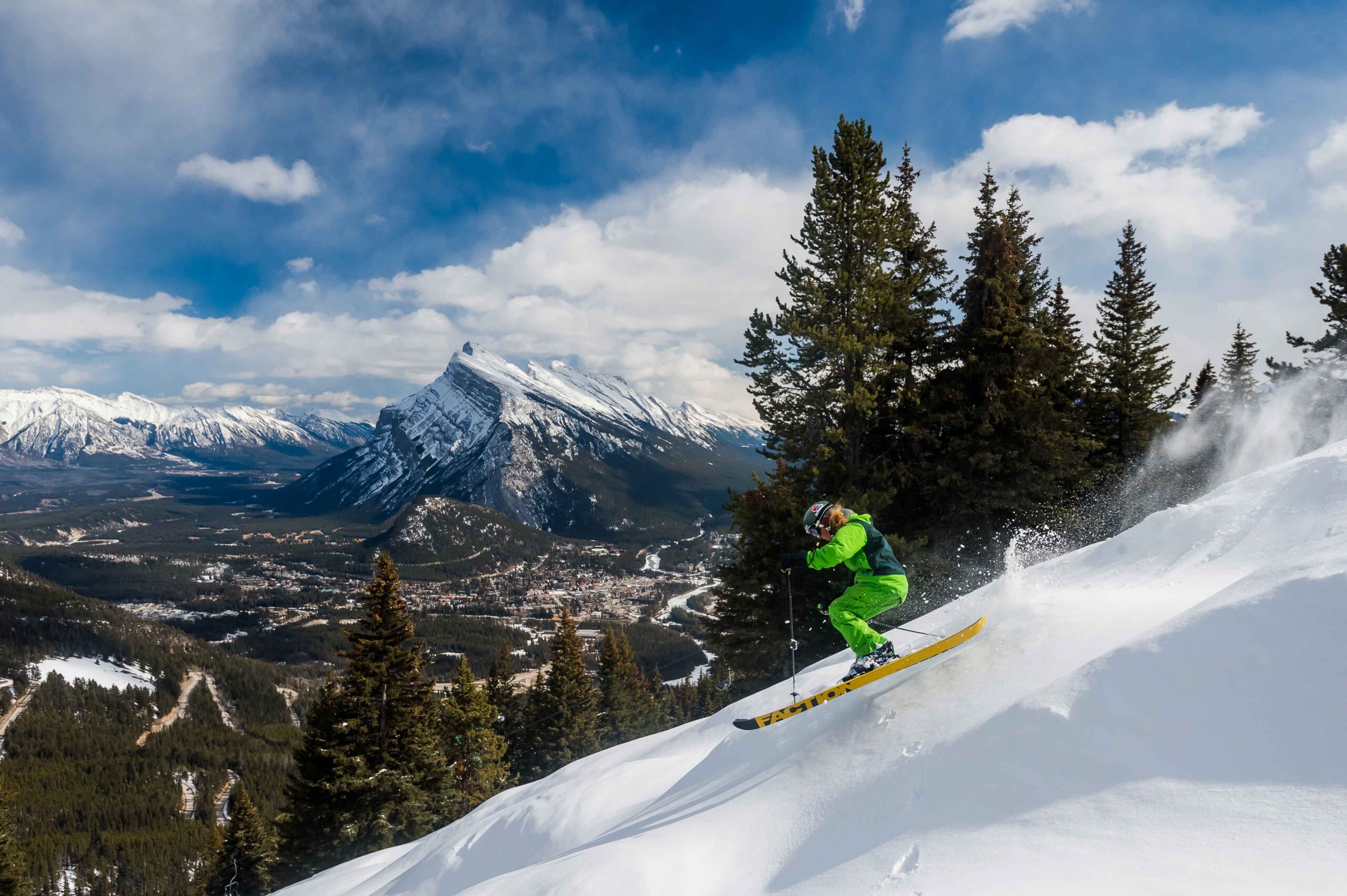 A skier comes down the slopes at Mt Norquay with a view of Rundle Mountain in the background