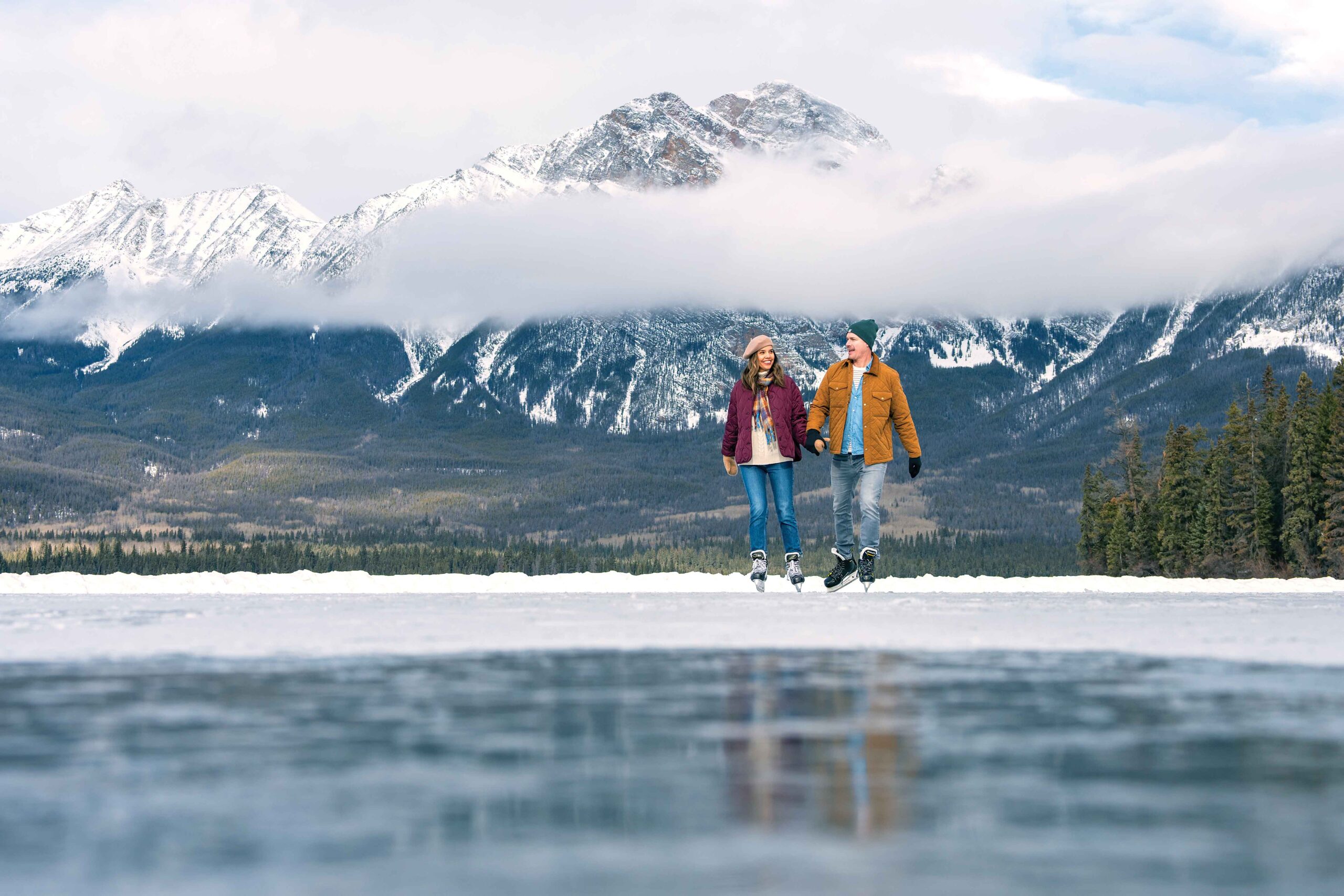 A couple skates at Pyramid Lake, one of the iconic winter sights in Jasper
